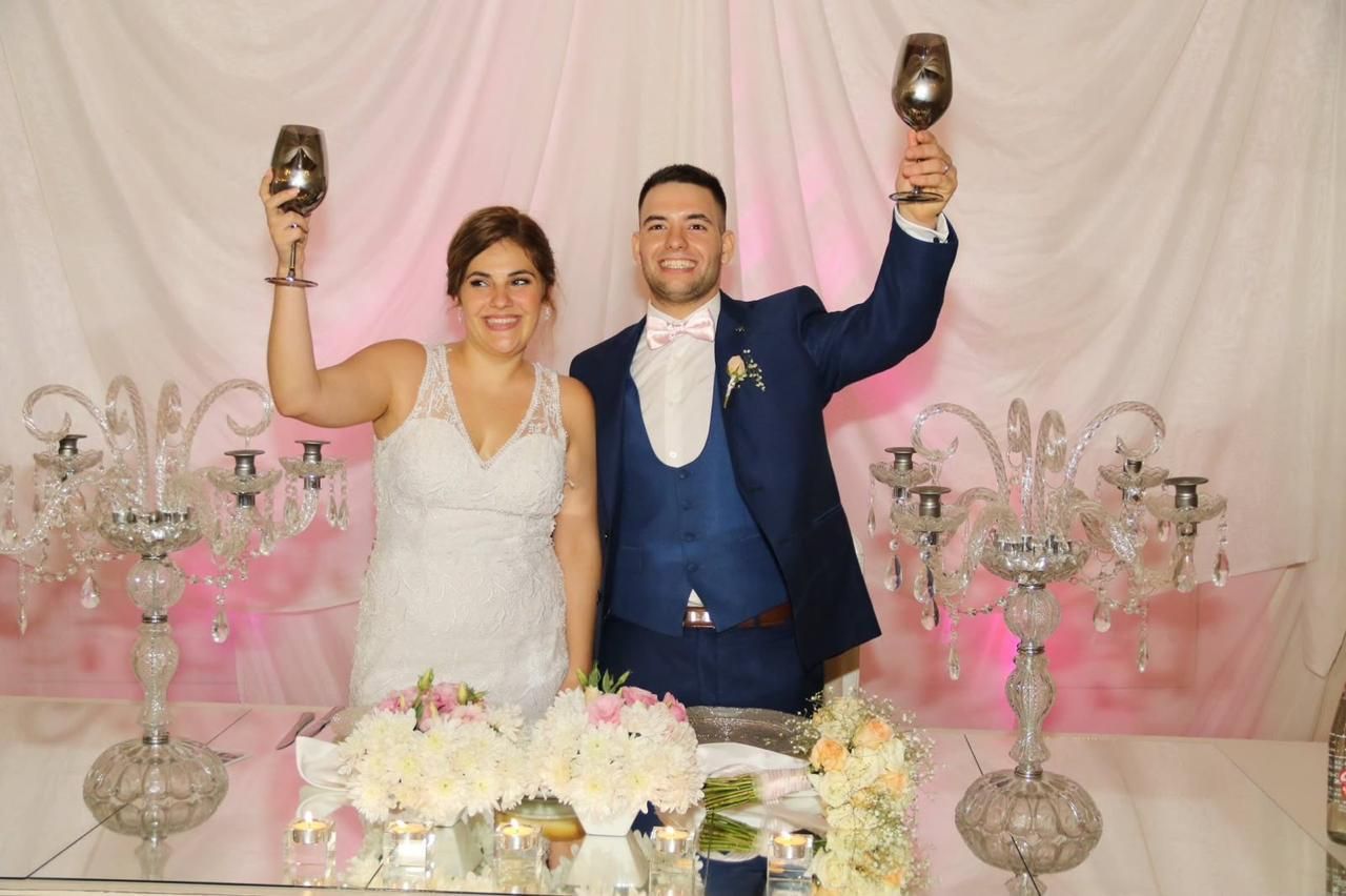 Los recién casados sonríen y brindan en una mesa decorada para la recepción de su boda.