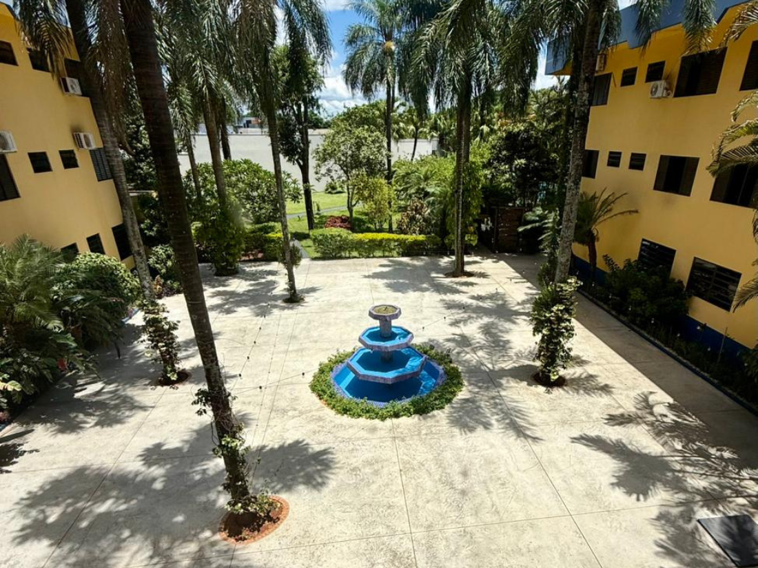 Pátio com fonte azul, palmeiras e edifícios amarelos em ambos os lados.