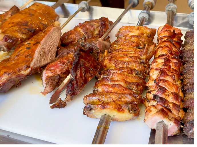 Espetos de carne marinada grelhando na churrasqueira.