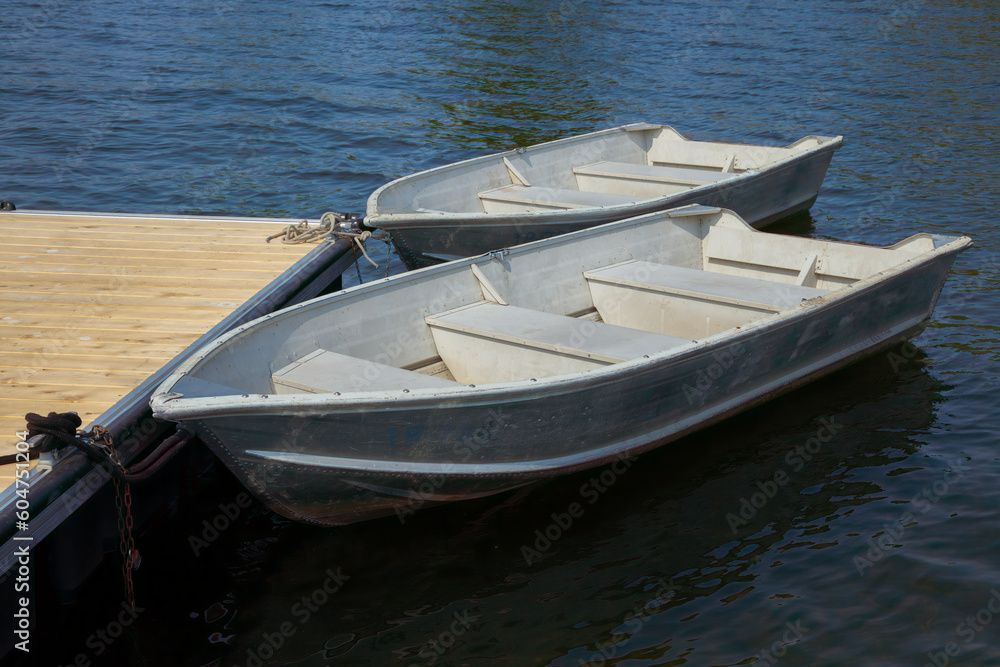 Deux petits bateaux de pêche blancs et bleus amarrés à un quai en bois.