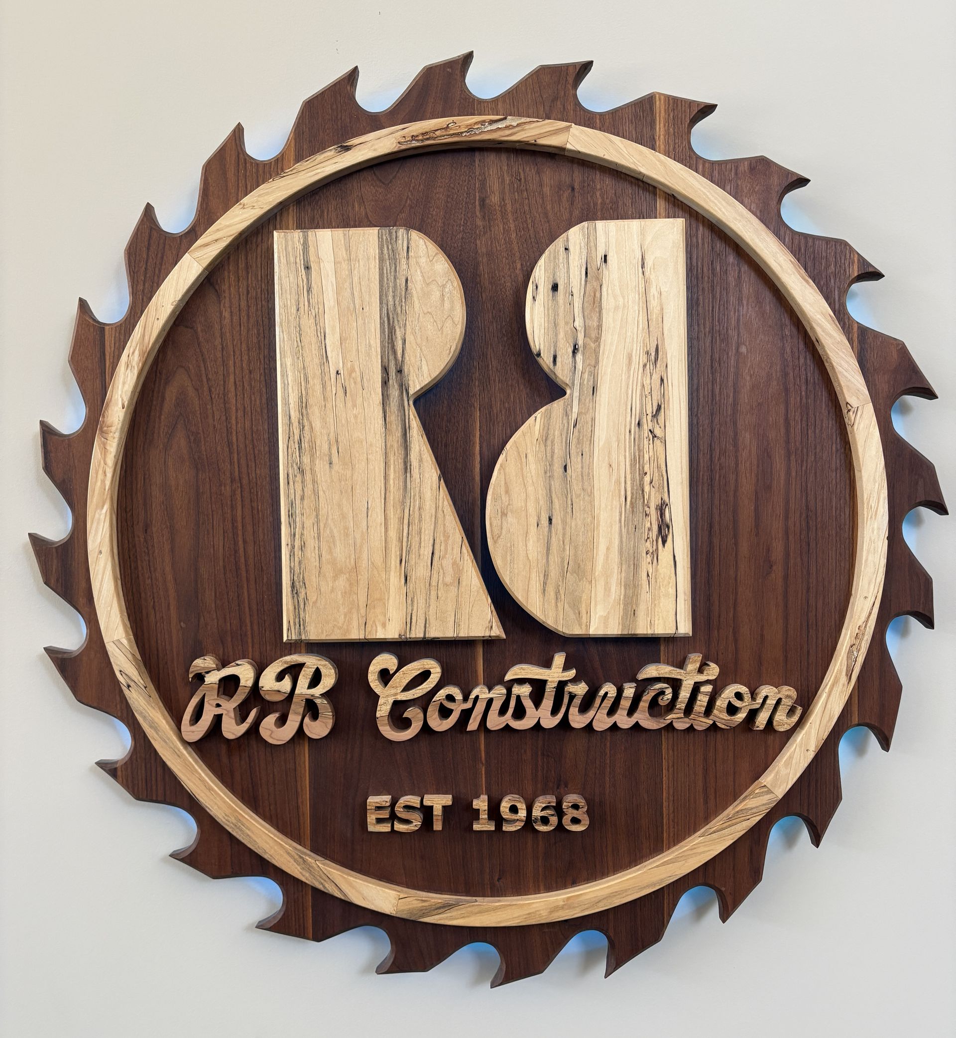RB Construction wooden logo sign with circular saw blade edge and “EST 1958” text