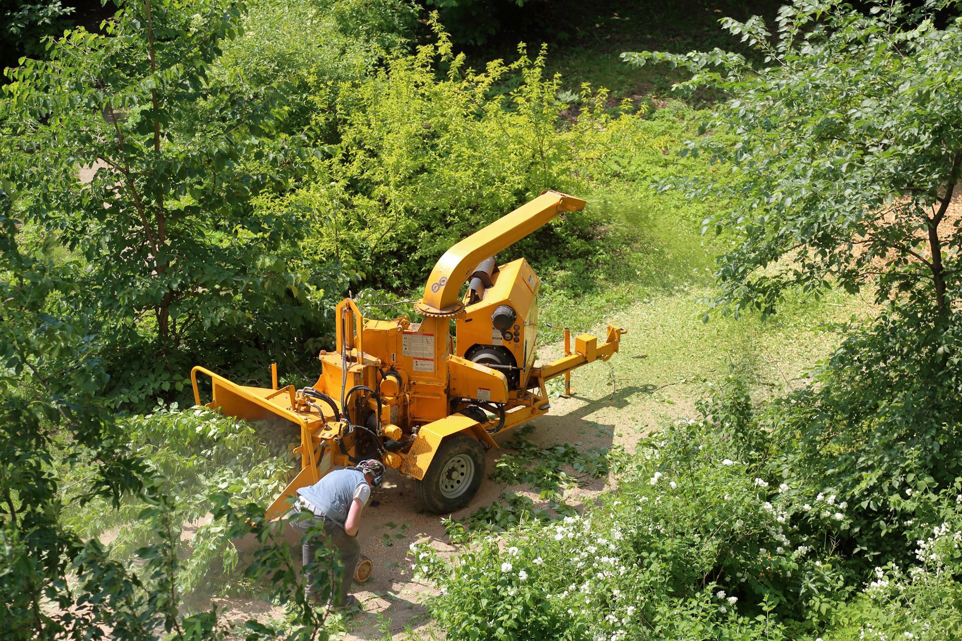 A man is working on a tree chipper in the woods