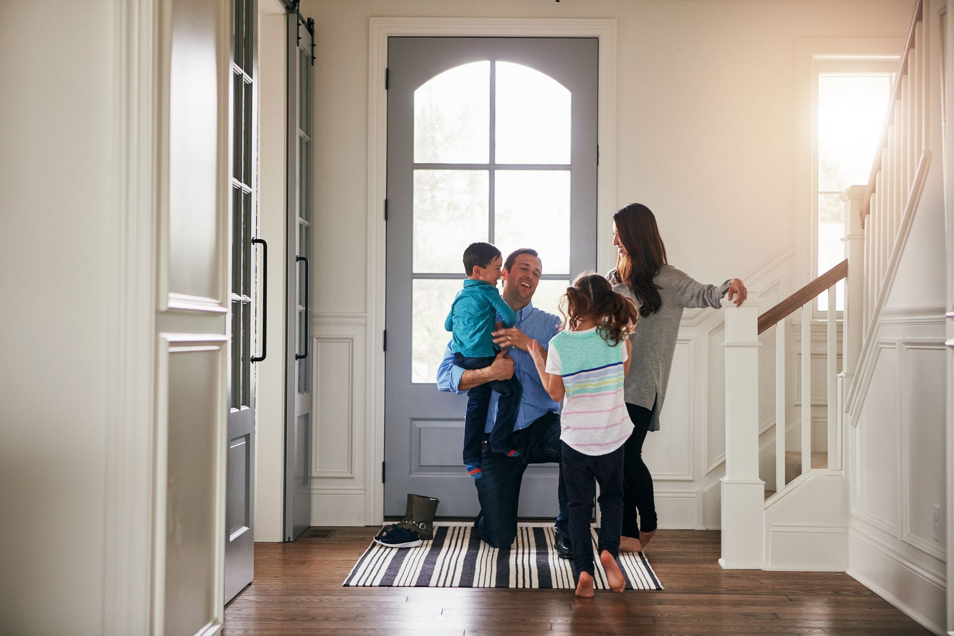 Family gathered in a bright entryway, smiling and talking near the front door
