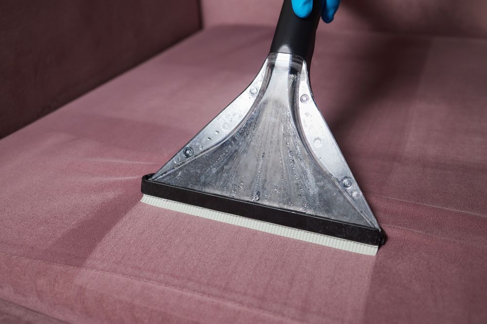 A Person is Cleaning a Pink Couch With a Vacuum Cleaner — Furniture & Auto Pride in Port Macquarie, NSW