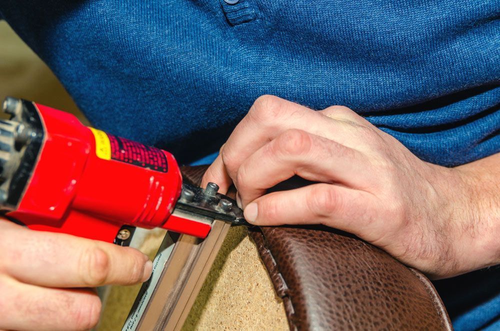 Man Fixing a Chair With a Handheld Tool — Furniture & Auto Pride in Old Bar, NSW