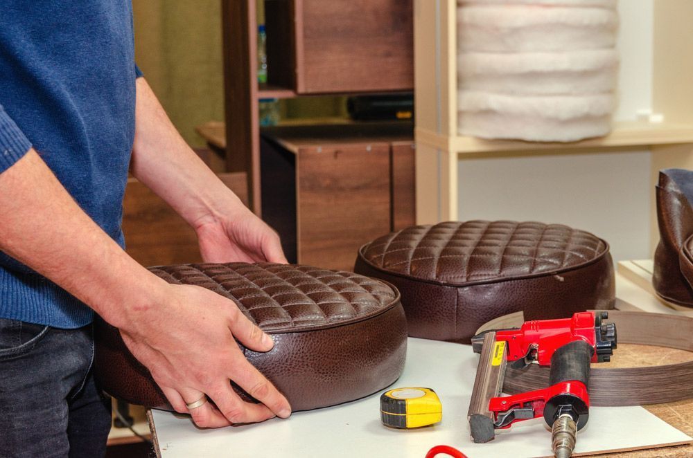 A Man is Working on a Brown Leather Ottoman — Furniture & Auto Pride in Lake Cathie, NSW
