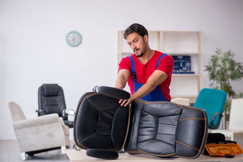 A man is repairing an office chair in a living room — Furniture & Auto Pride in Bonny Hills, NSW
