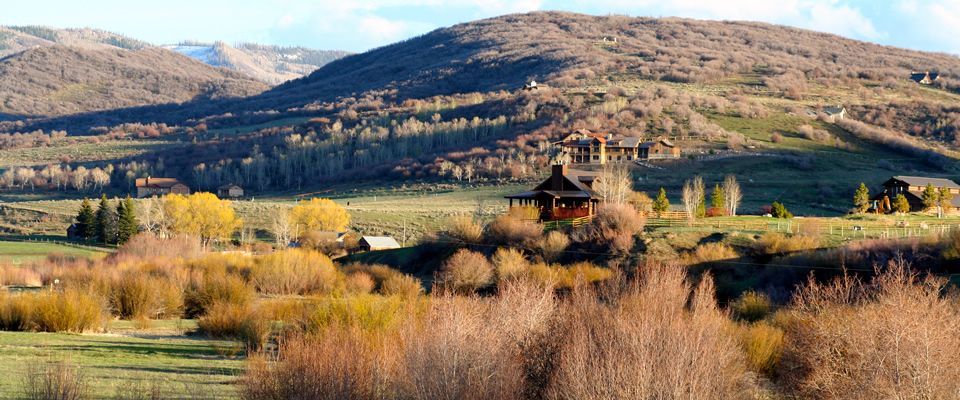 A house in the middle of a field with mountains in the background.
