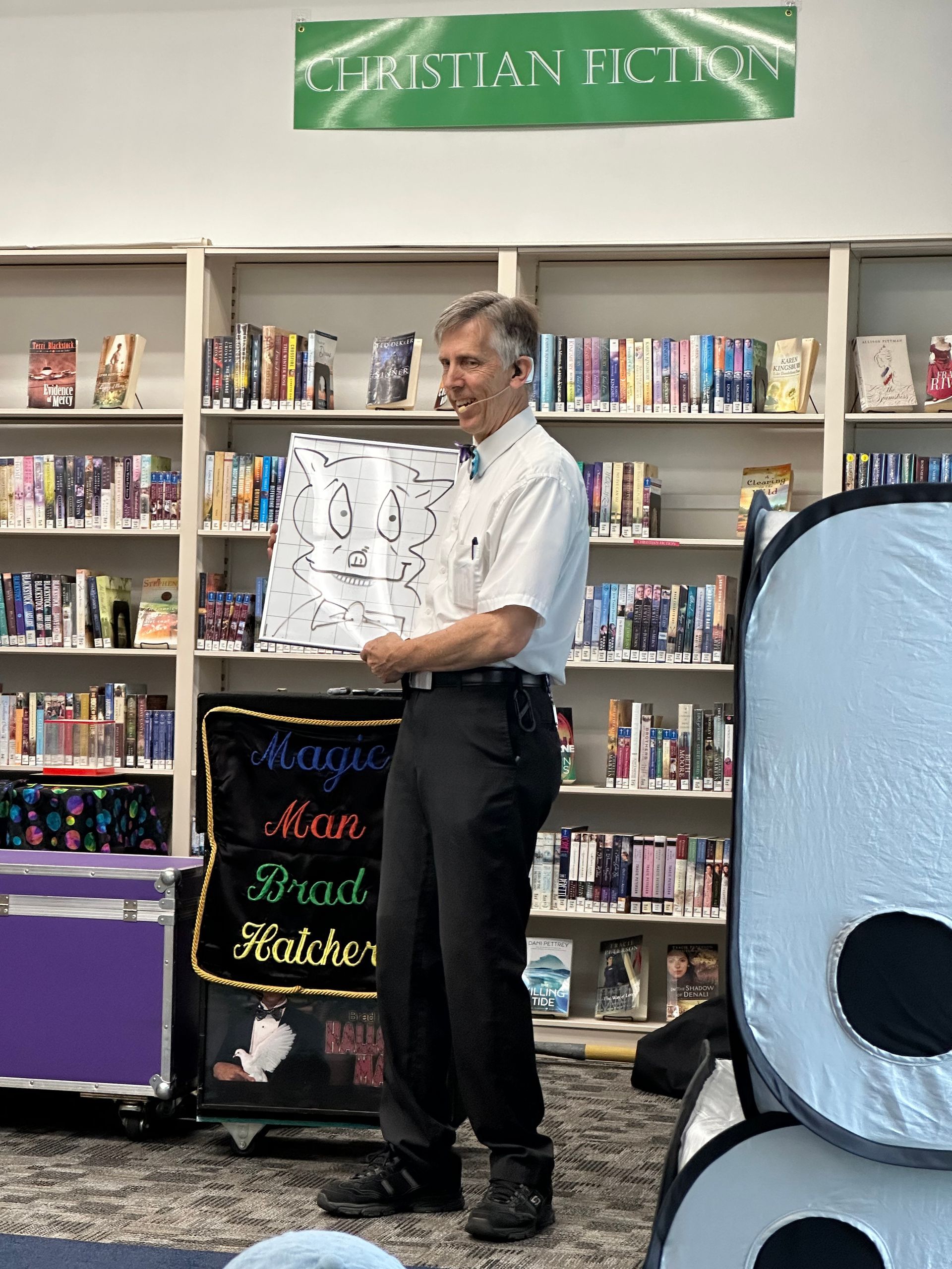 A man is standing in front of a bookshelf holding a piece of paper.