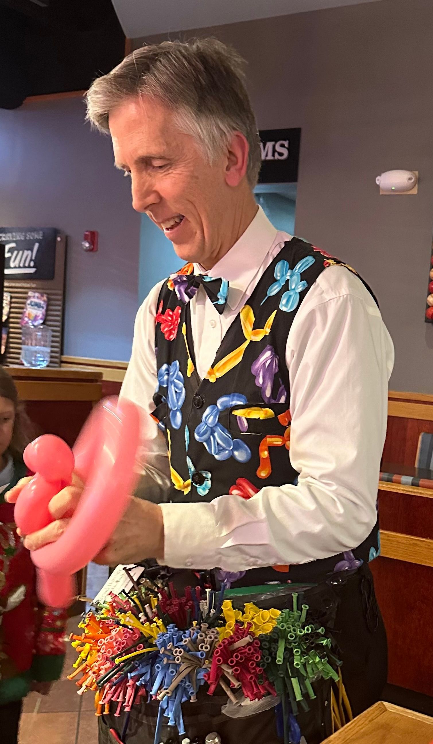 A man in a white shirt and black pants is holding a plastic container in a library.