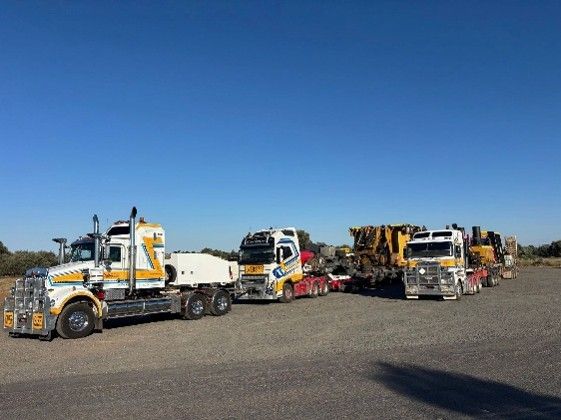 A group of trucks parked in a spacious parking lot under clear blue skies.
