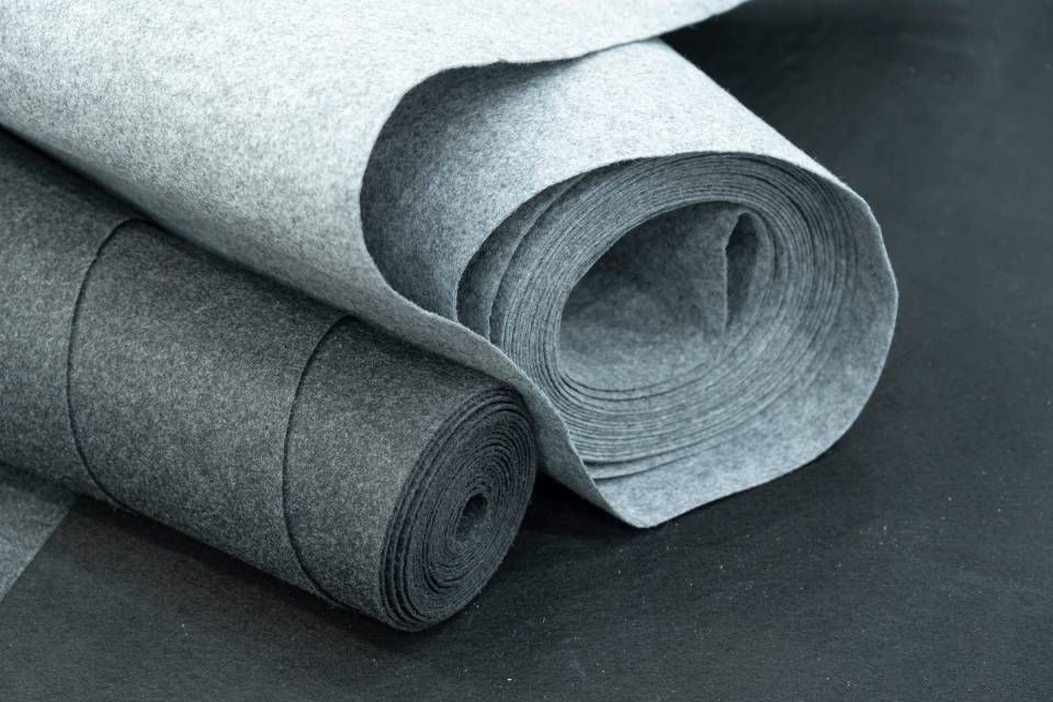 Rolled gray and white fabric bolts on a dark surface