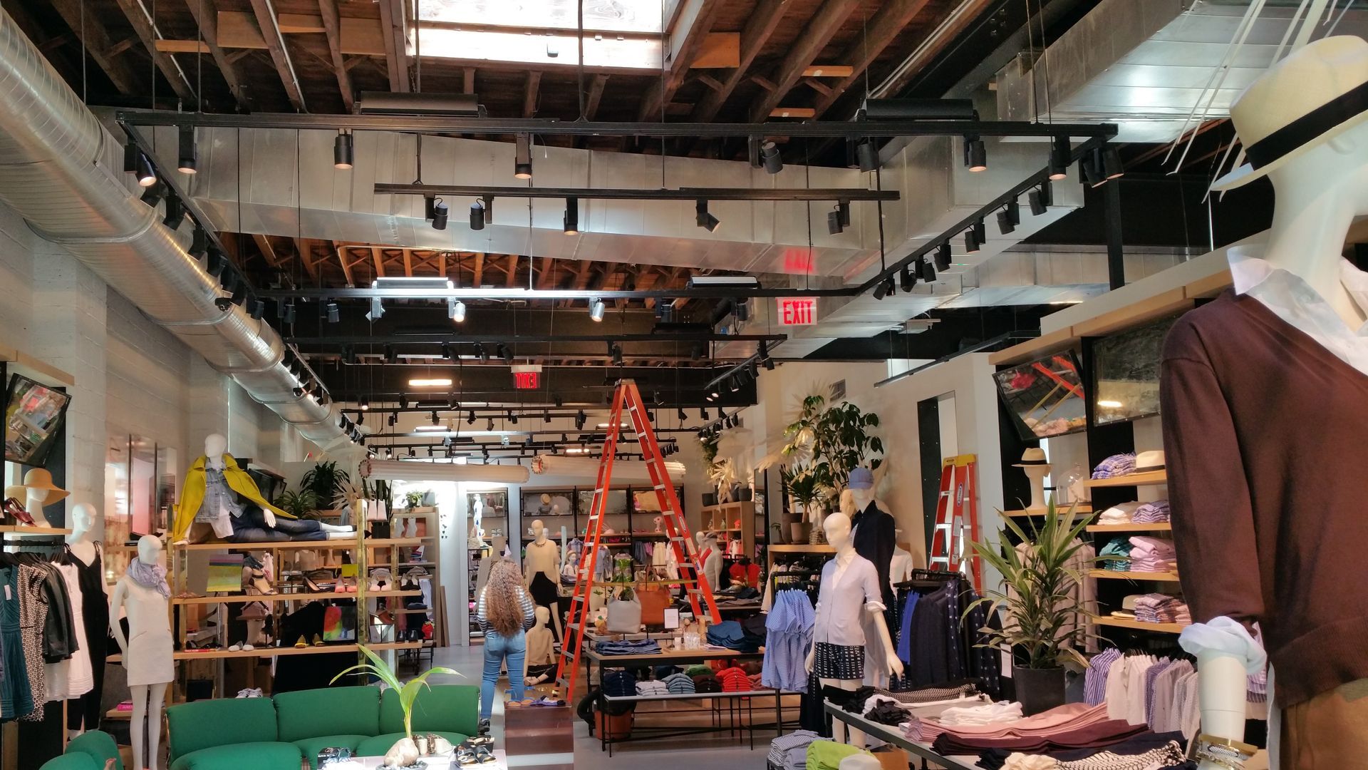 The inside of a clothing store with mannequins and a green couch.