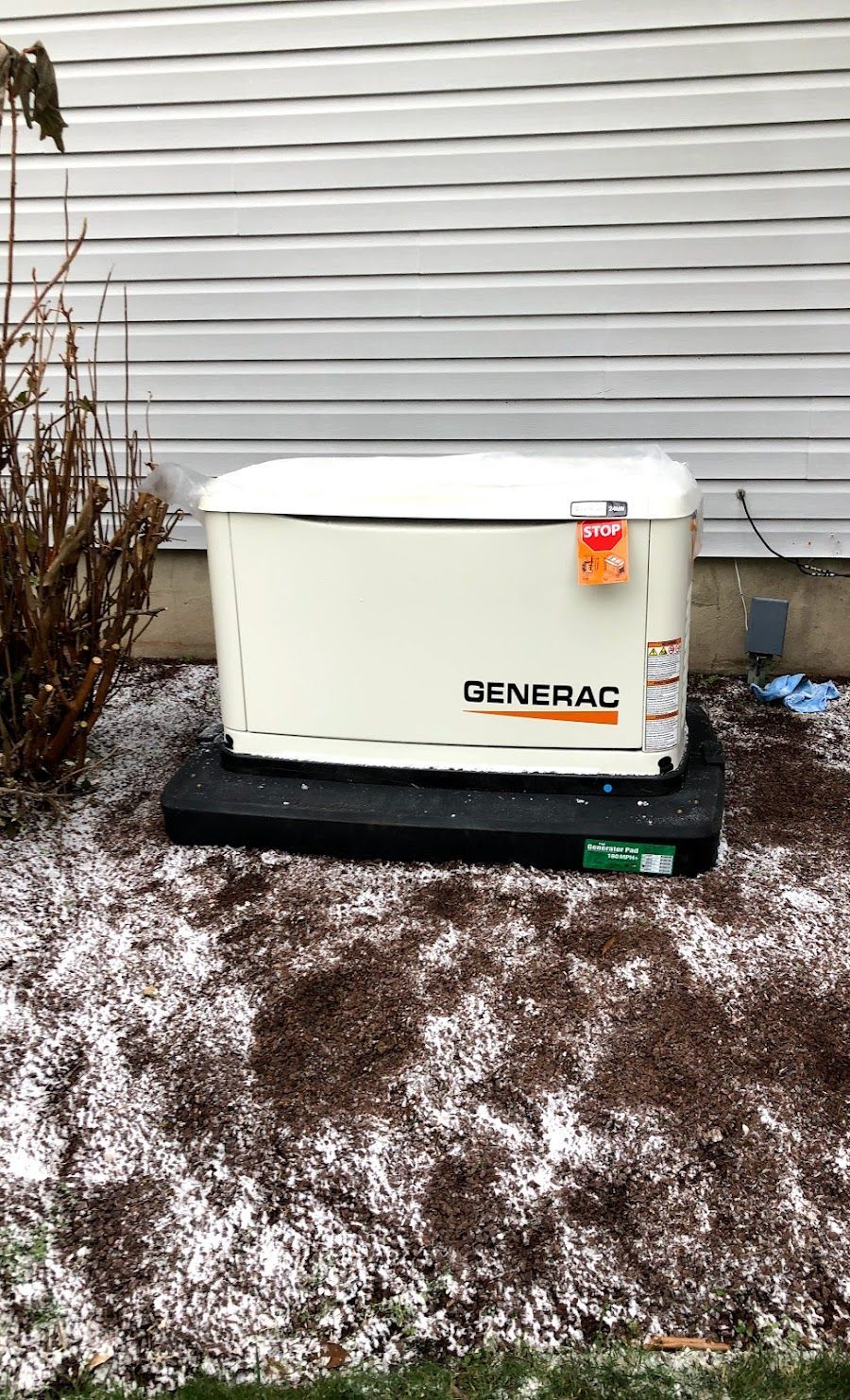 A generator is sitting in the dirt in front of a house.