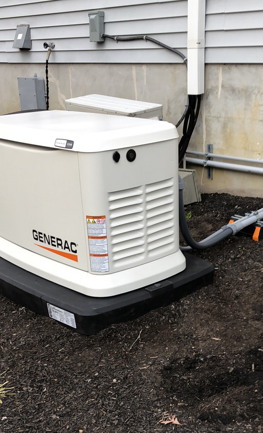 A generator is sitting on the ground in front of a house.