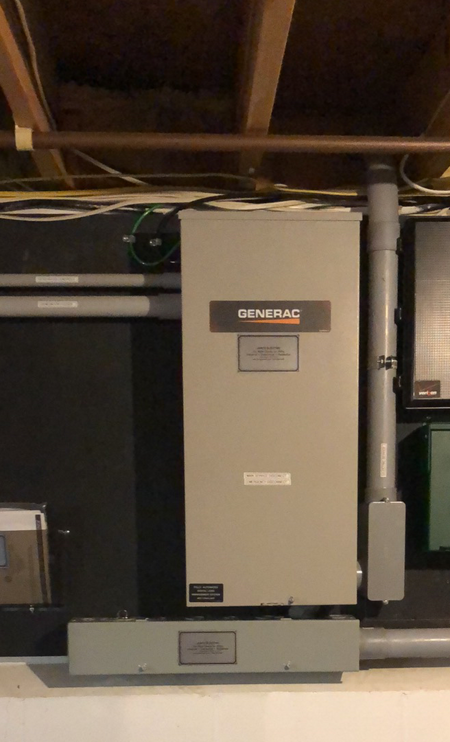 A generator is sitting on a wall in a basement.