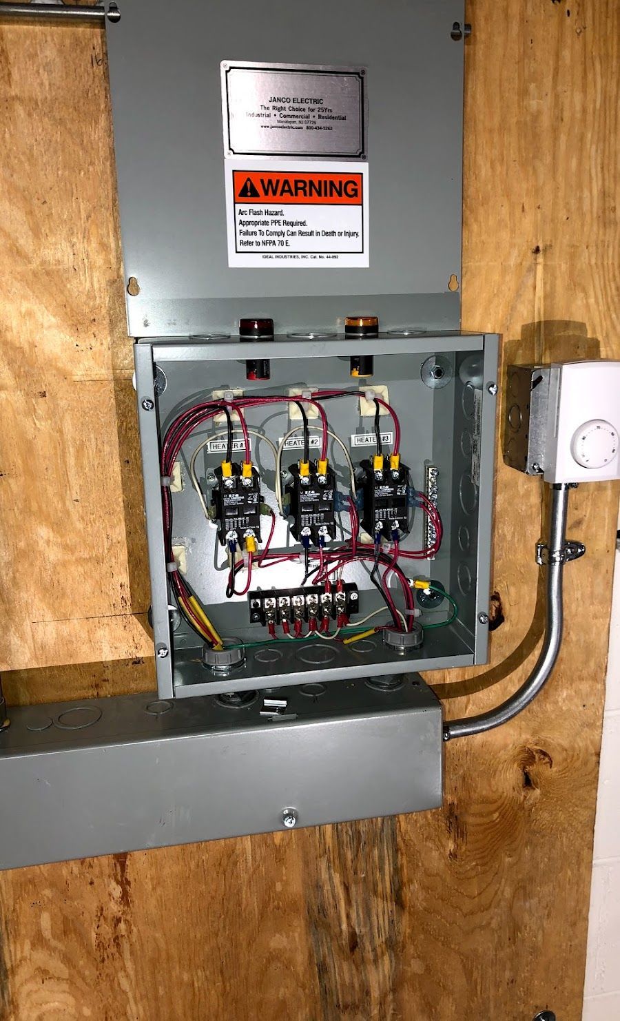 A electrical box is hanging on a wooden wall.