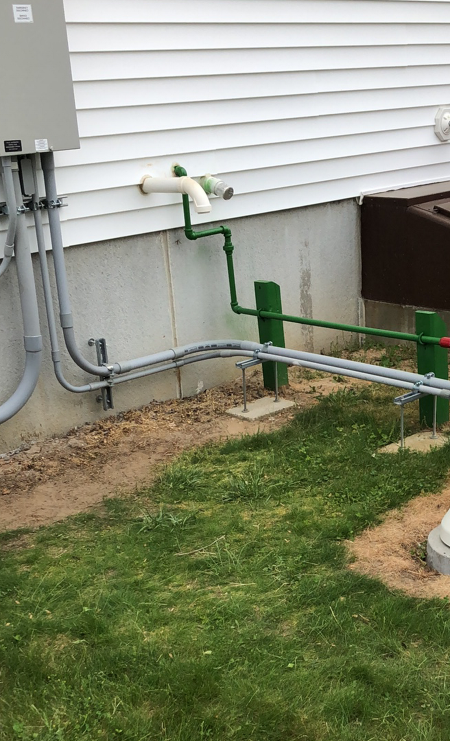 A green pipe is connected to a white house.