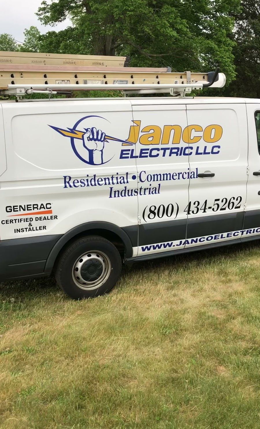 A white van is parked in a grassy field.
