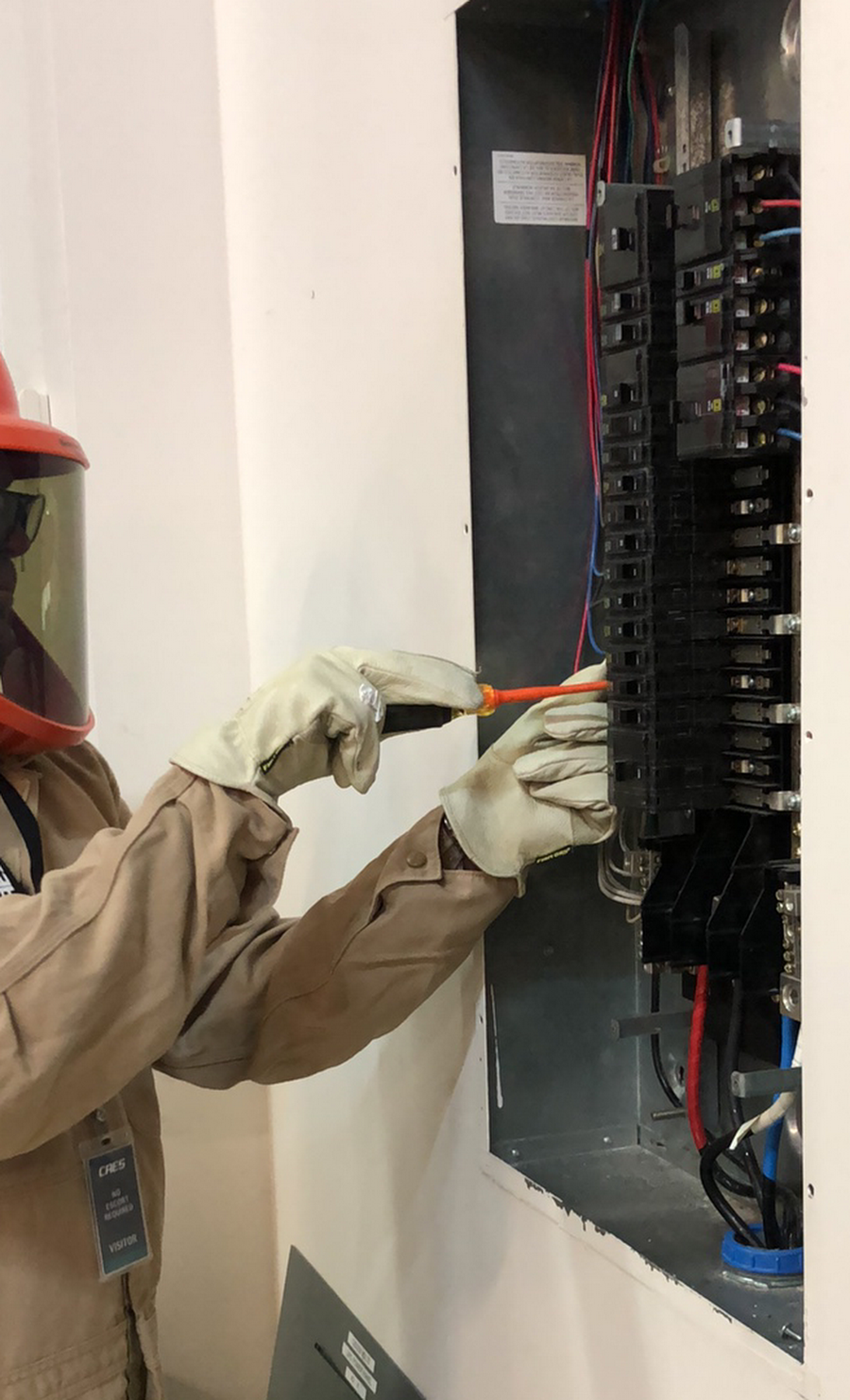 A man is working on an electrical box with a screwdriver.