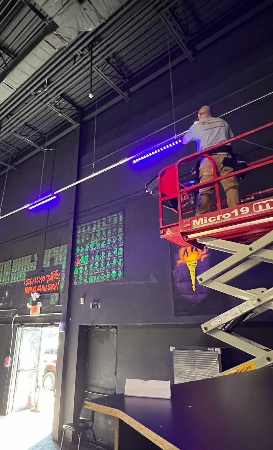 A man is standing on a scissor lift in a building.