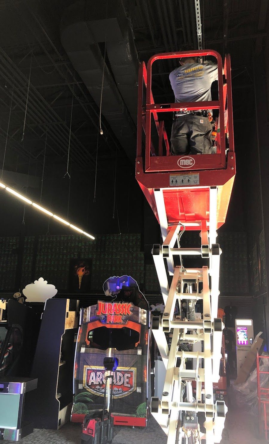 A man is sitting on a ladder in front of an arcade machine.