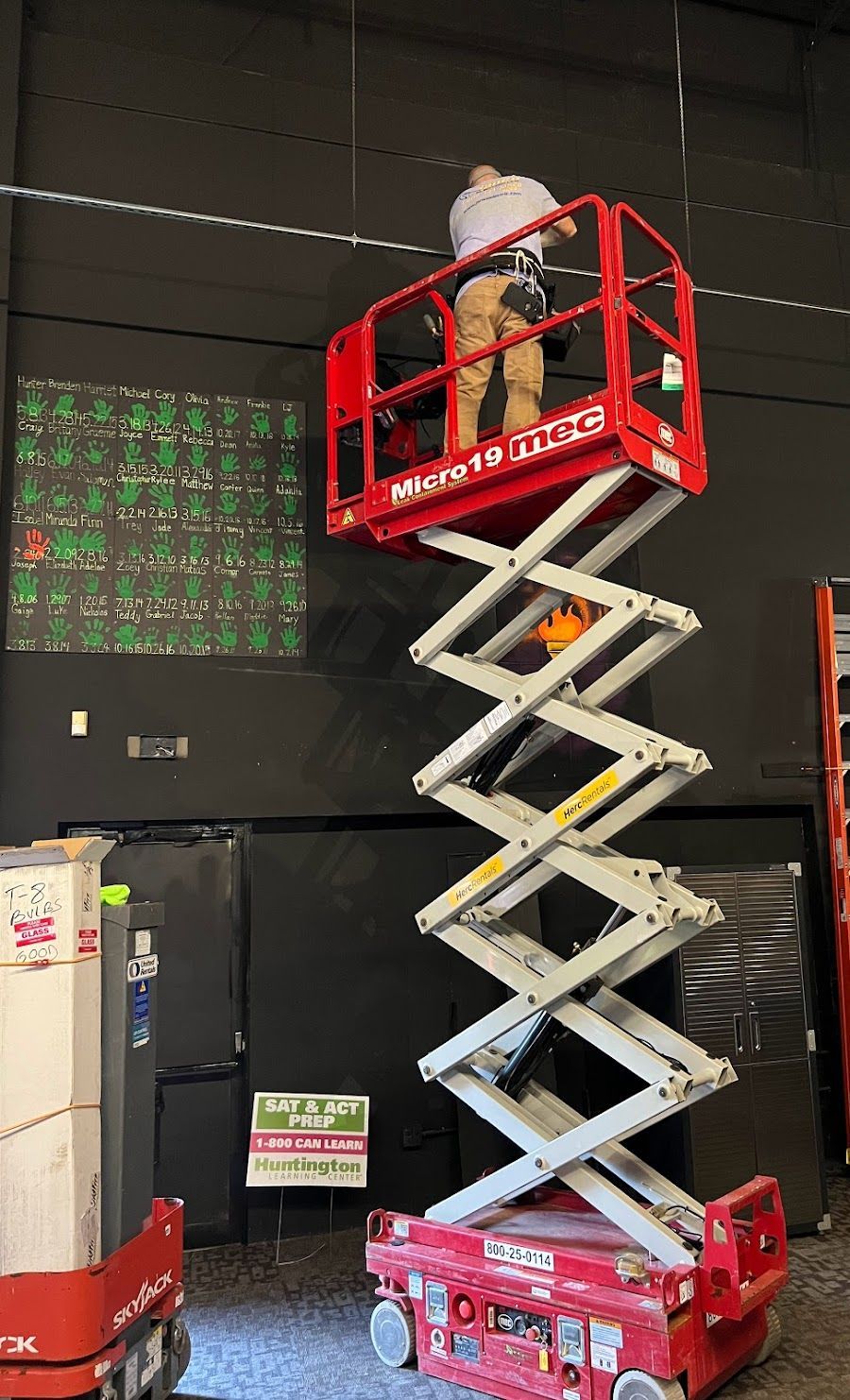 A man is standing on a scissor lift in a warehouse.