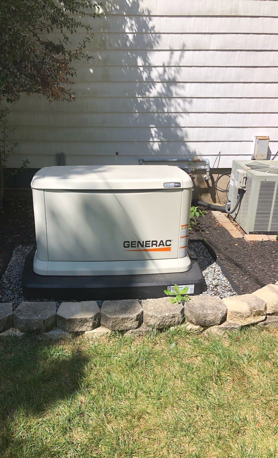 A generator is sitting in the grass in front of a house.