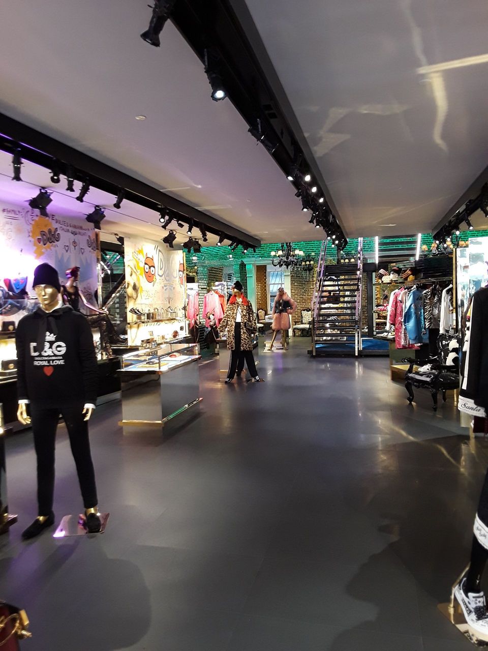 A man is standing in the middle of a clothing store.