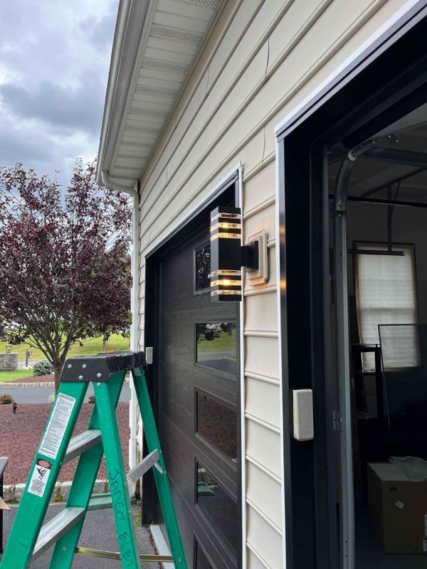 A green ladder is sitting next to a garage door.