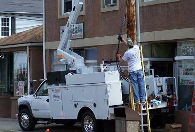 A man is standing on a ladder next to a utility truck