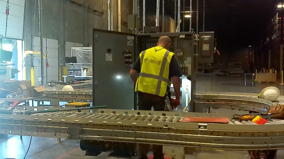 A man in a yellow vest is working on a machine