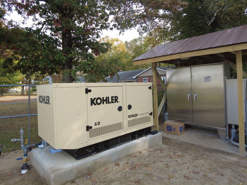A kohler generator is sitting under a wooden shed.
