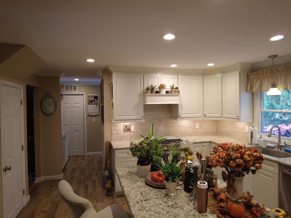 A kitchen with white cabinets , granite counter tops , a sink , and a clock on the wall.