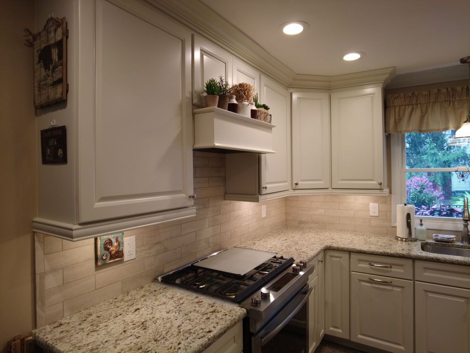 A kitchen with white cabinets , granite counter tops , a stove and a sink.