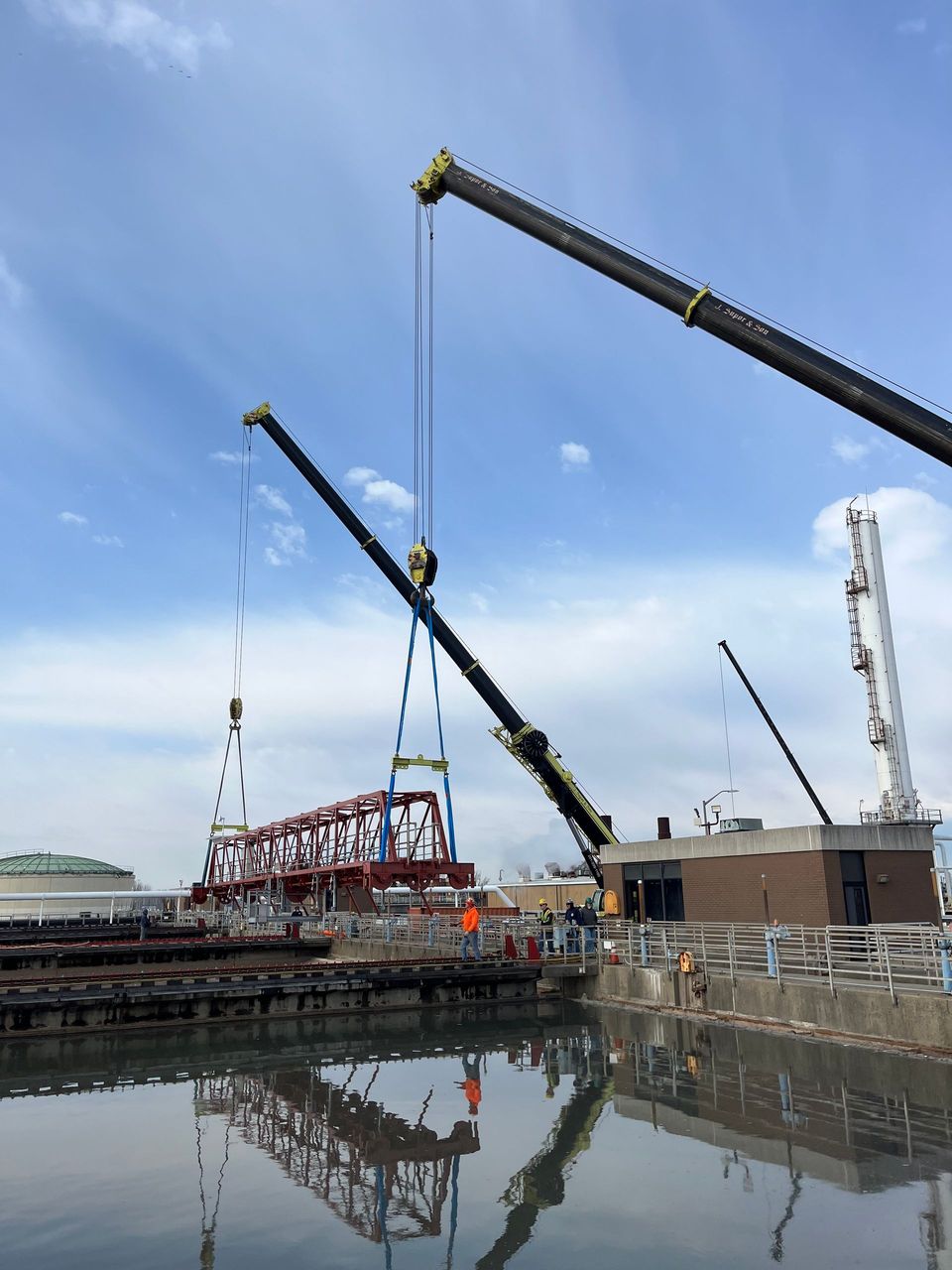 A large crane is lifting something over a body of water