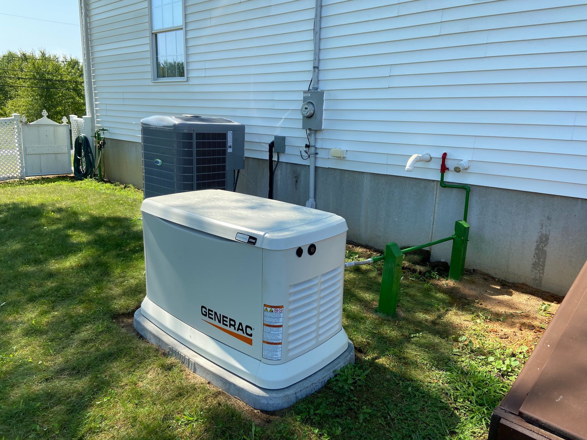 A generator is sitting in the grass in front of a house.