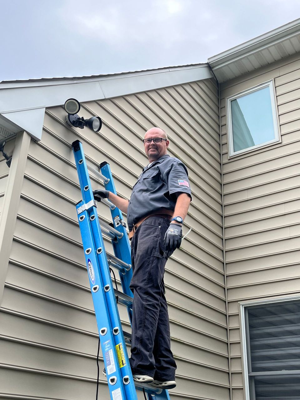 A man is standing on a ladder in front of a house.