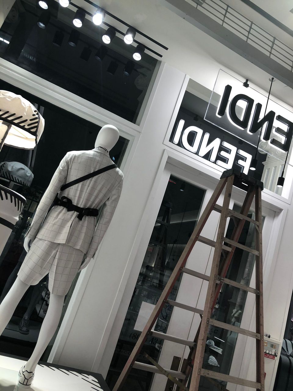 A mannequin is standing in front of a sign that says fendi