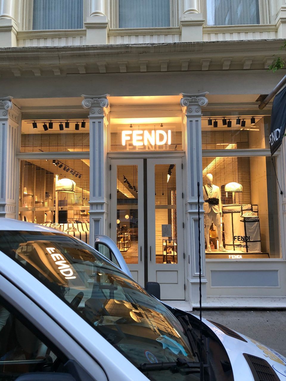 A white van is parked in front of a fendi store