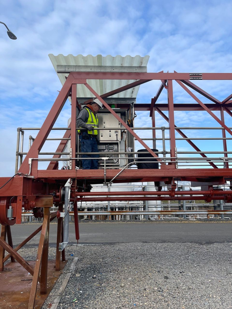 A man in a yellow vest is working on a metal structure