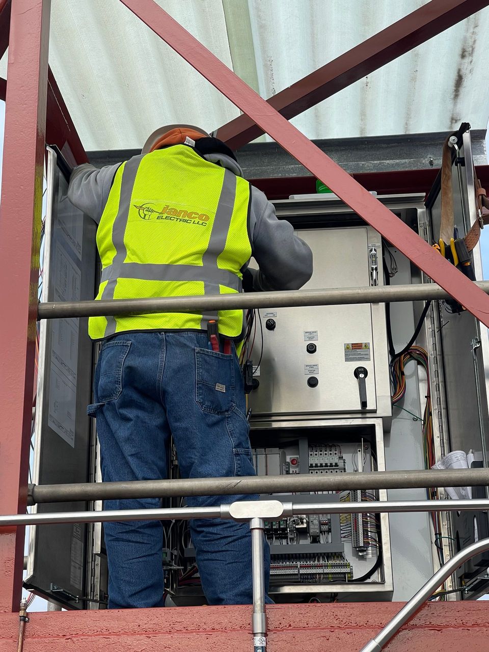 A man in a yellow vest is working on a machine