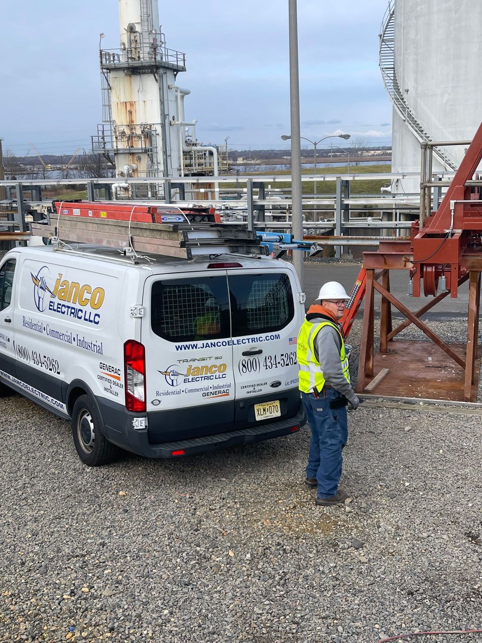 A man in a hard hat is standing next to a white van.