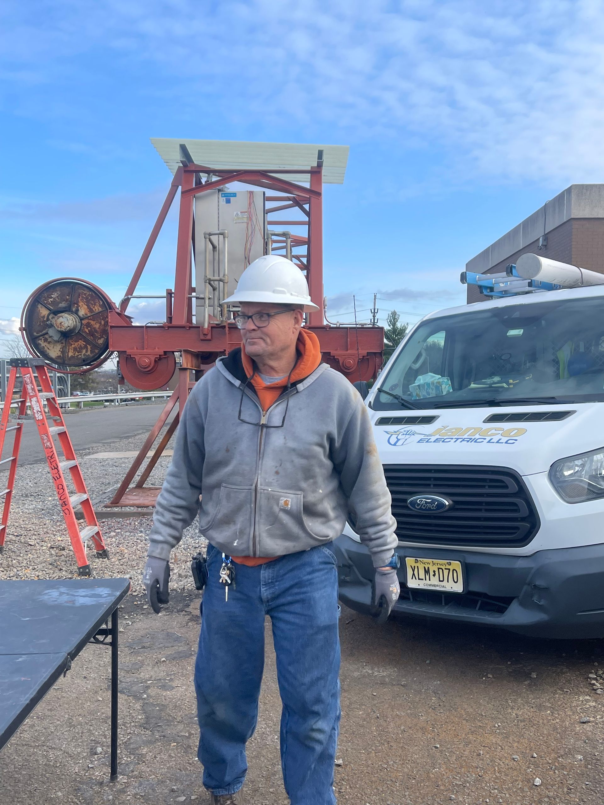 A man wearing a hard hat is standing in front of a white van.