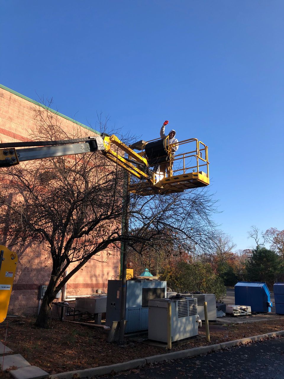 A man is standing on a lift in front of a building.