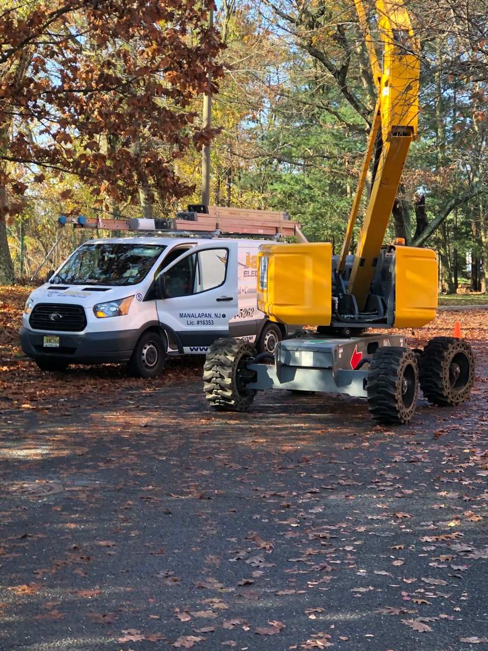 A white van is parked next to a yellow crane.