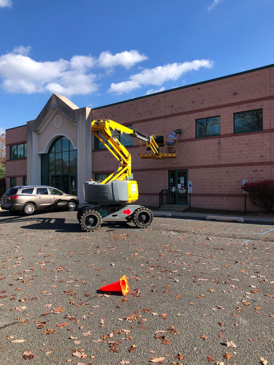 A yellow crane is sitting in front of a large brick building.