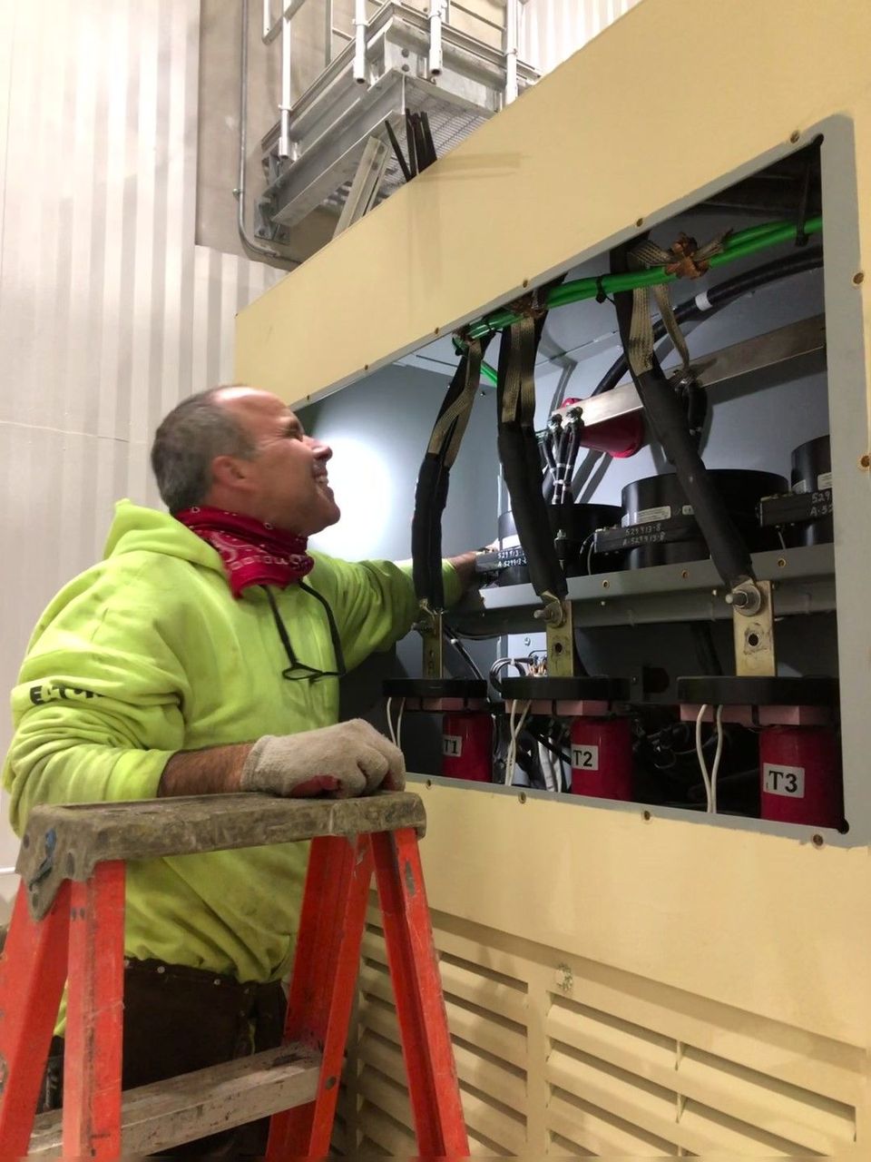 A man is sitting on a ladder working on a machine.