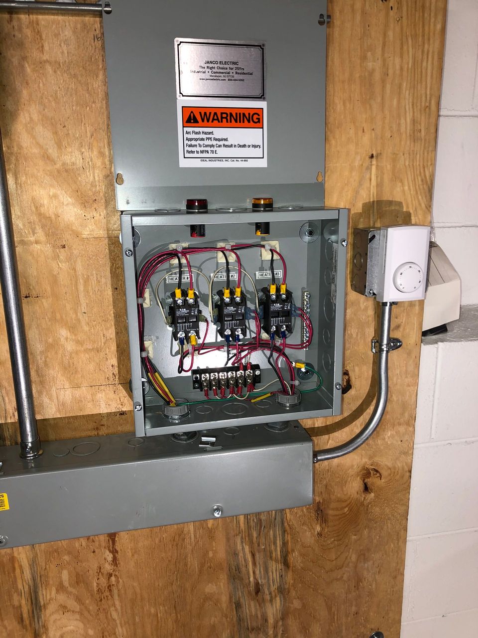 A electrical box is hanging on a wooden wall.