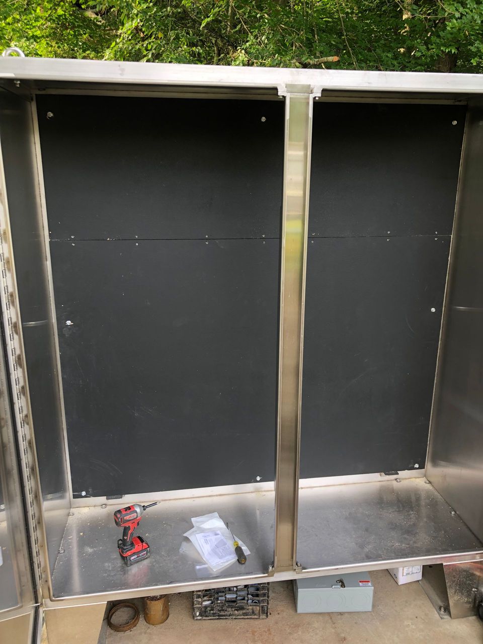 A stainless steel cabinet with a black door is being built.